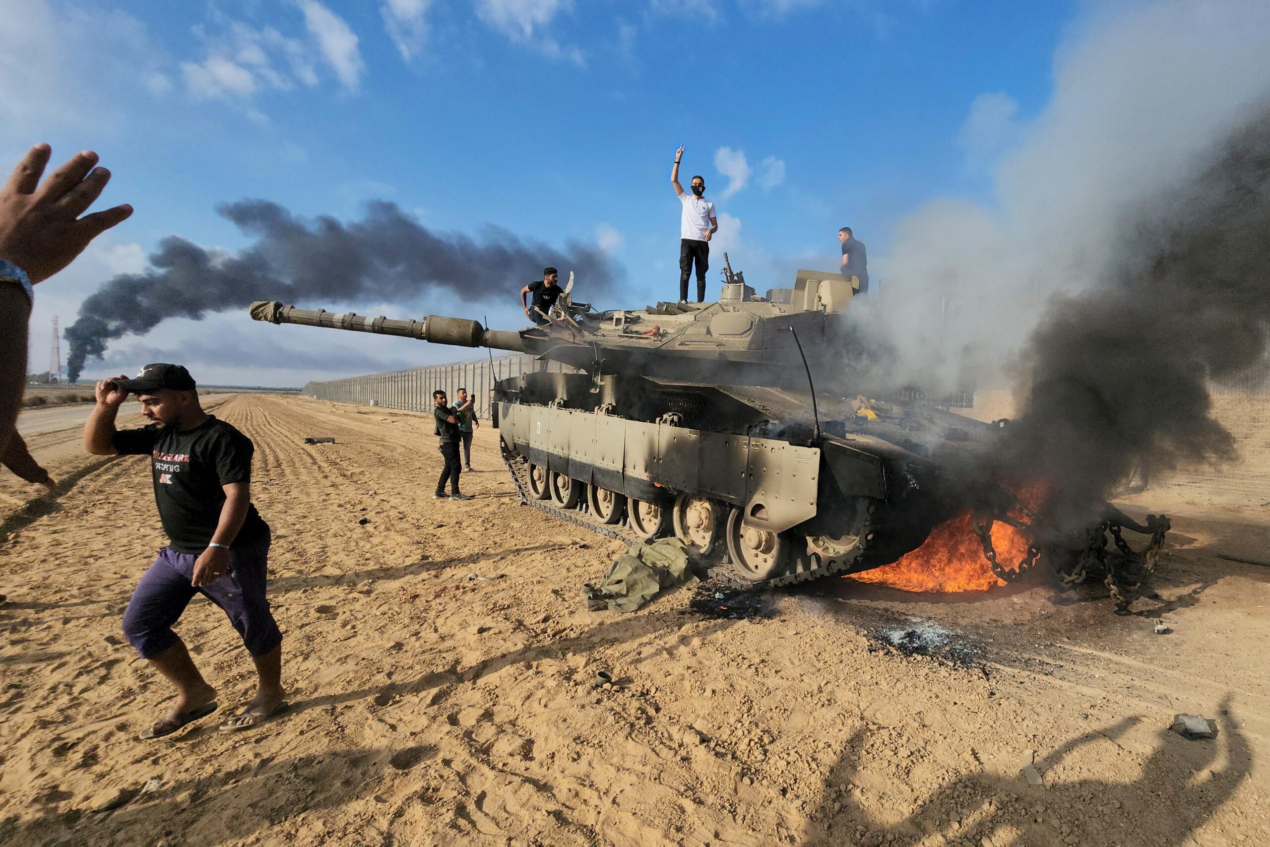 FILE – Palestinians celebrate by a destroyed Israeli tank at...