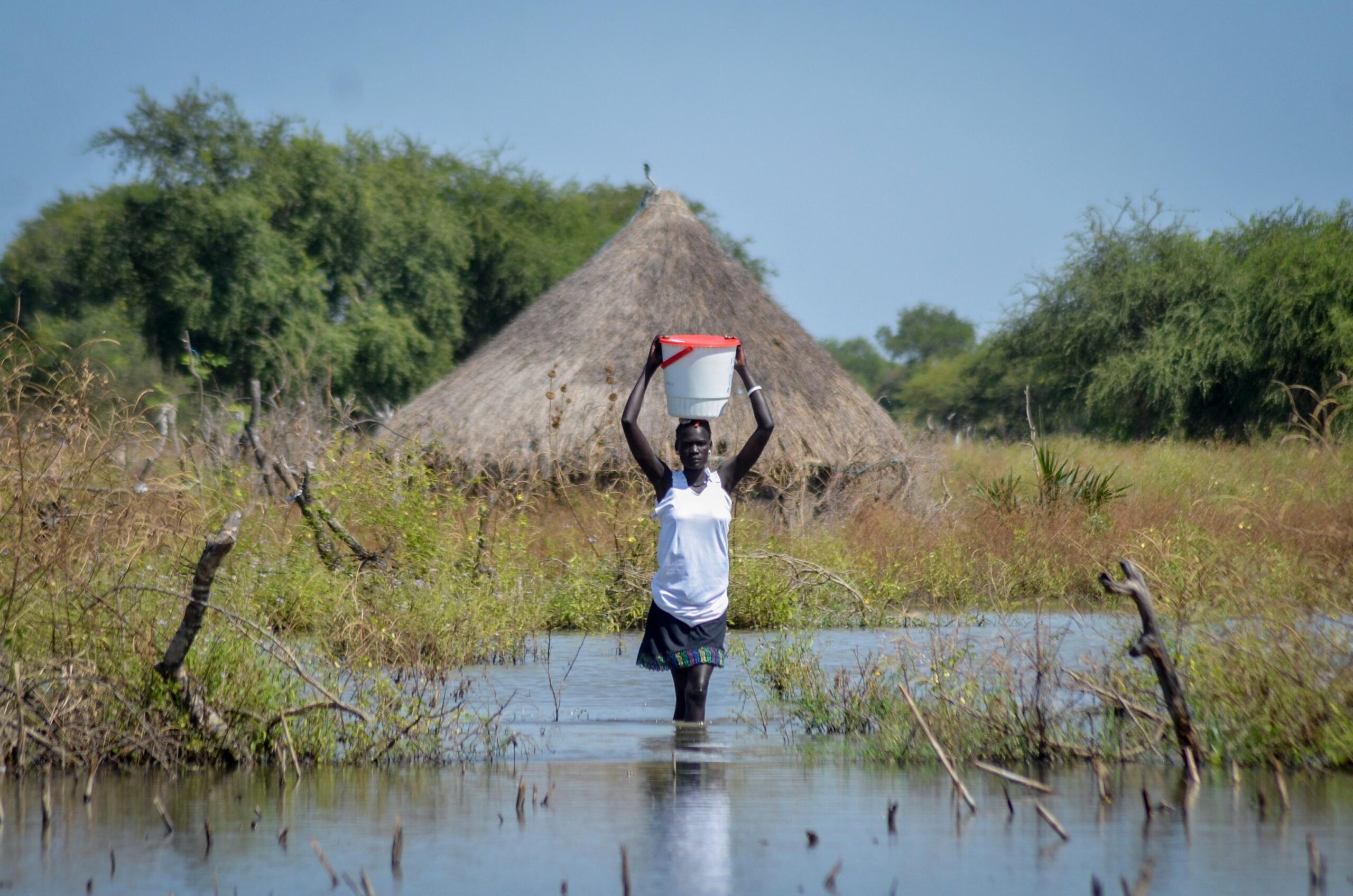 FILE – A woman carries a bucket on her head...