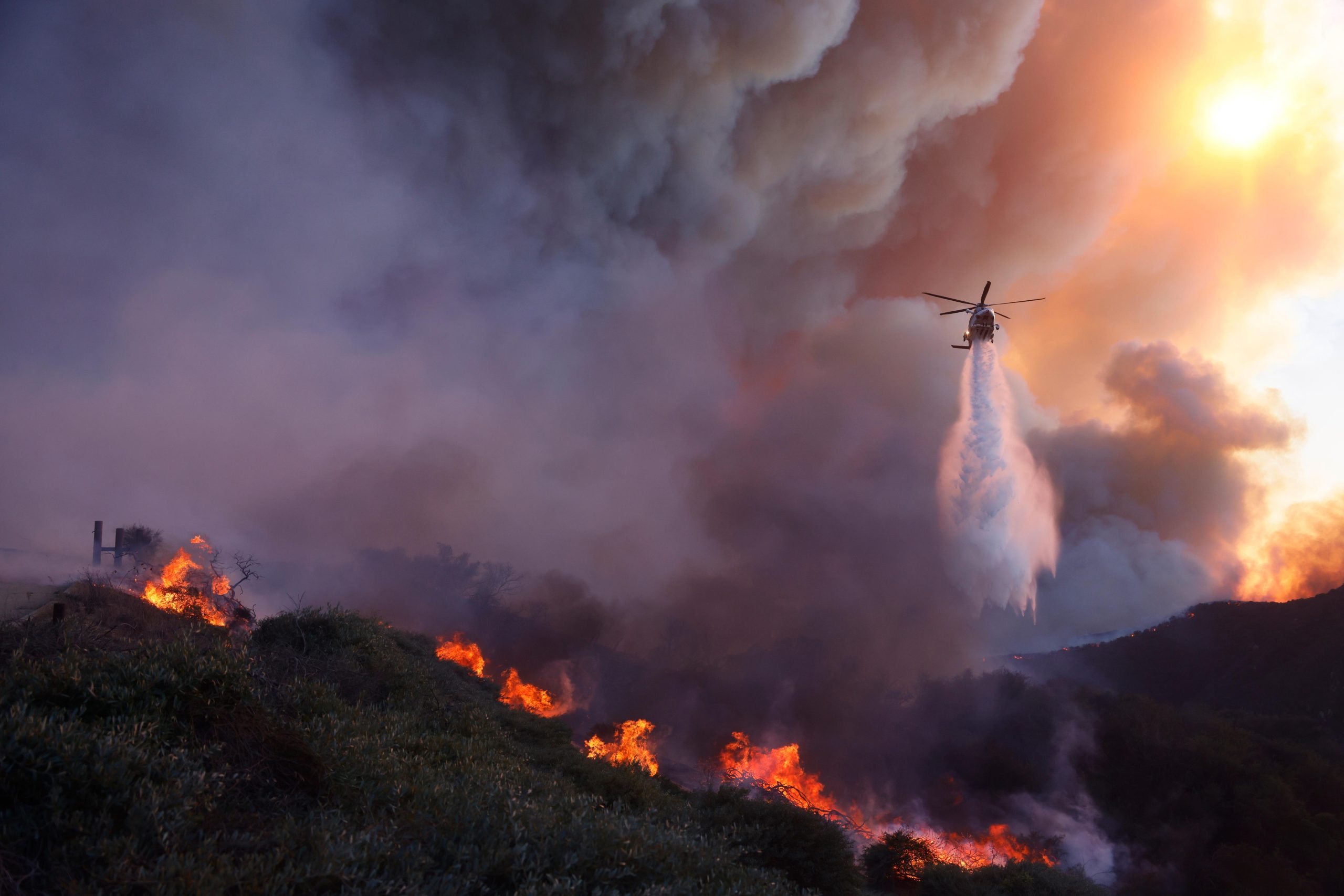 Water is dropped by helicopter on the advancing Palisades Fire...