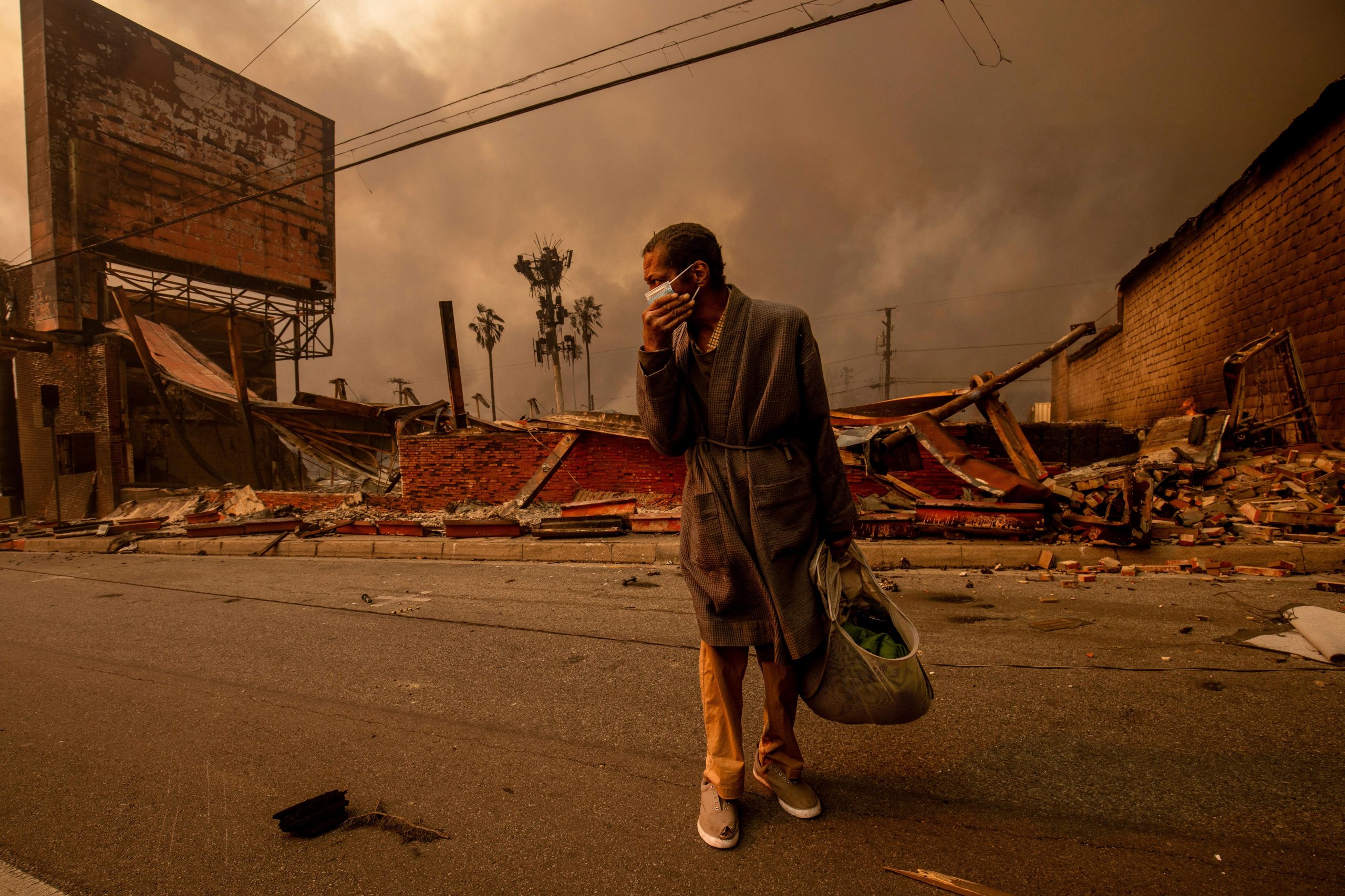 A man walks past a fire-ravaged business after the Eaton...