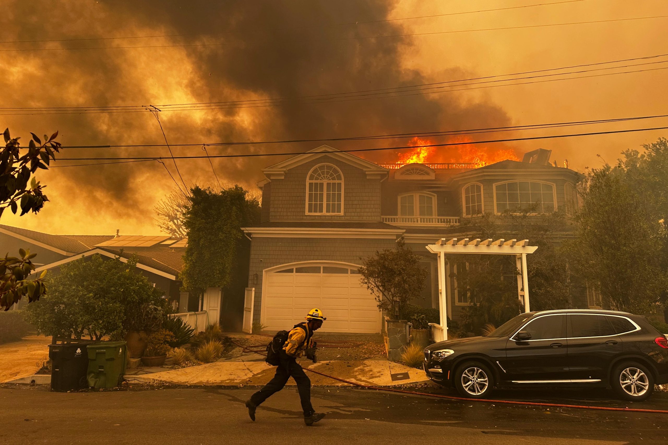 A residence burns as a firefighter battles the Palisades Fire...