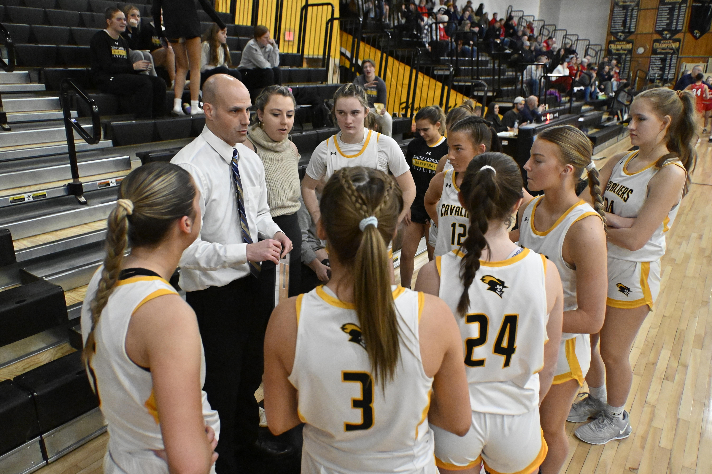 Coach Ryan Hutchinson speaks to his team during a basketball...