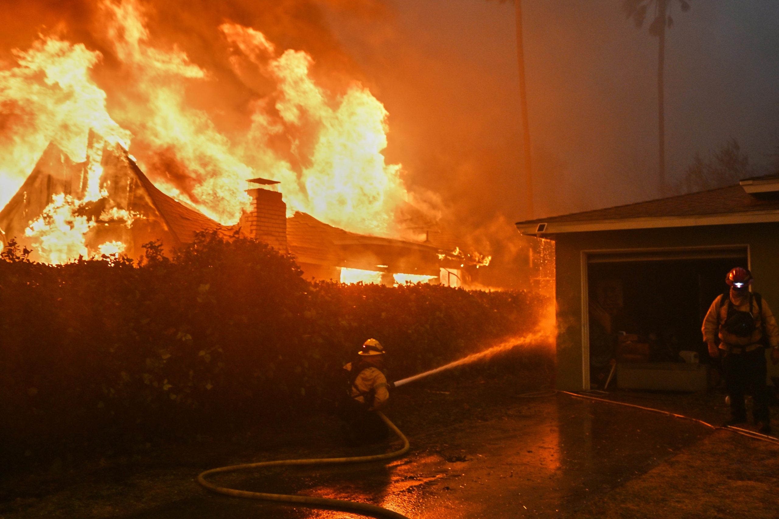 Fire crews battle the Eaton Fire next to a fully...