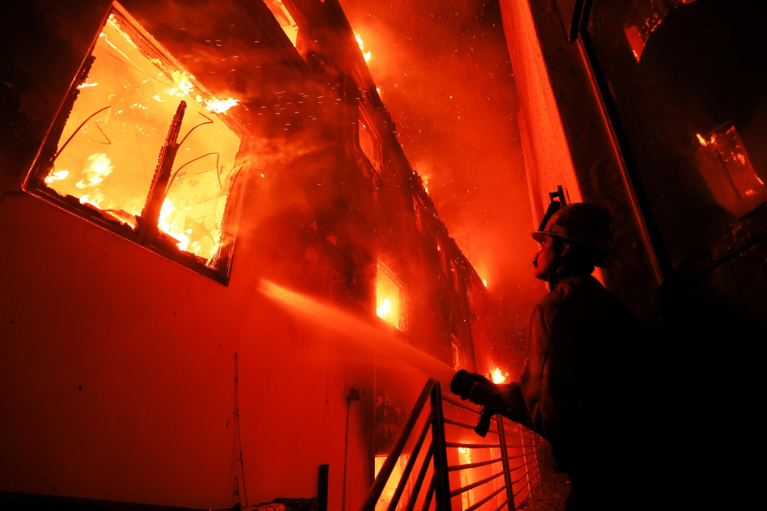 A firefighter works from a deck as the Palisades Fire...