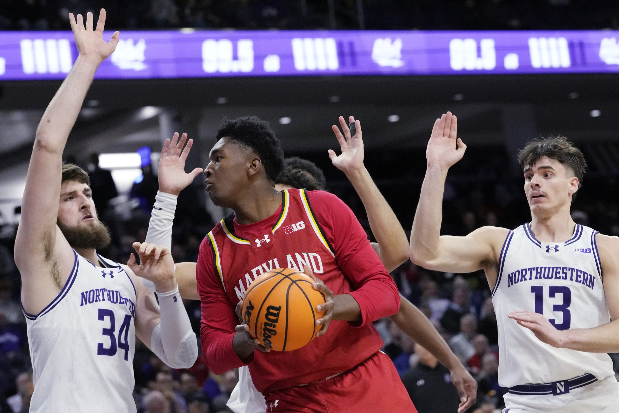 Maryland center Derik Queen, center, drives to the basket as...