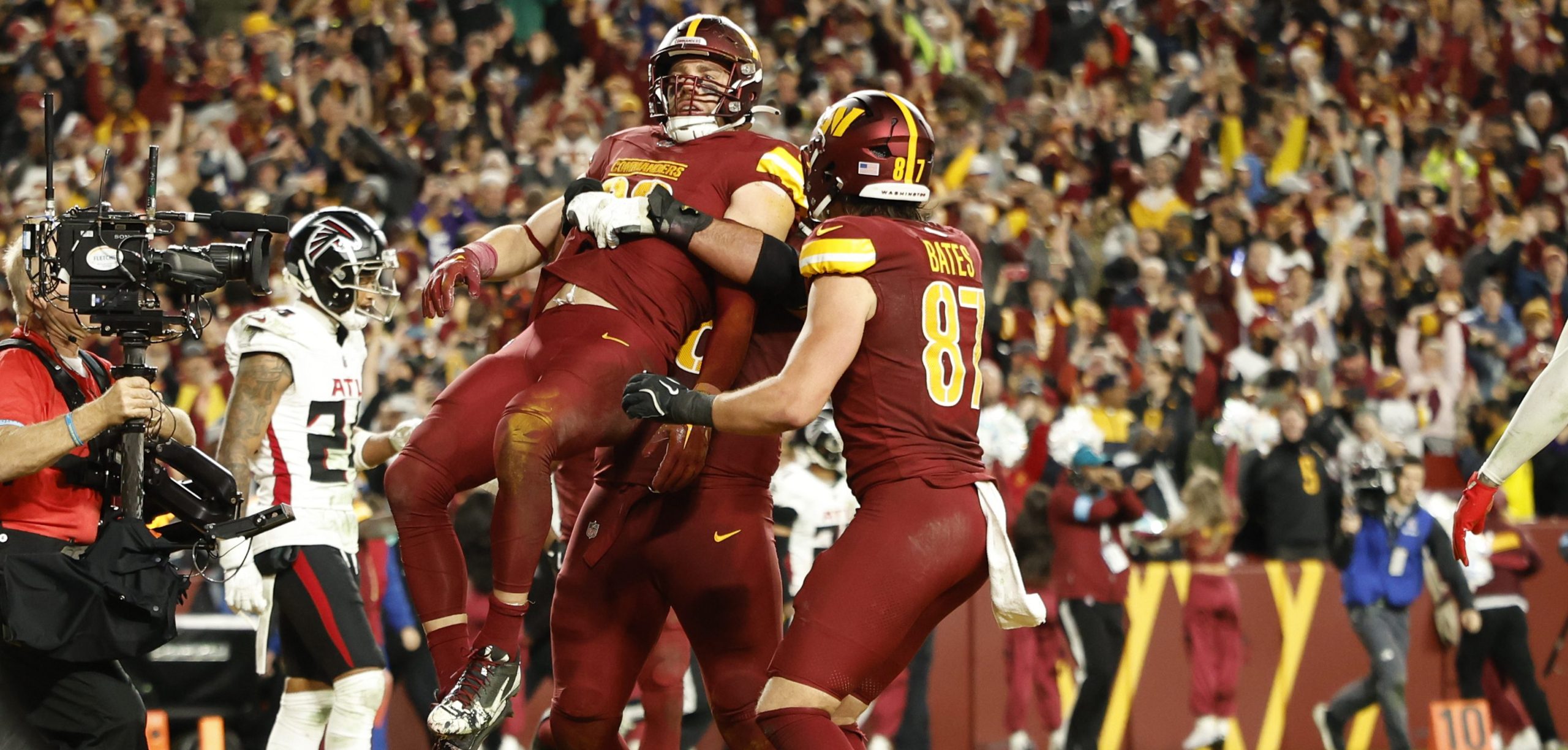 Washington Commanders tight end Zach Ertz (86) is lifted by a teammate after scoring the game-winning touchdown against the Atlanta Falcons in overtime of an NFL game at Northwest Stadium in Landover, Maryland.